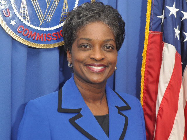 A smiling Mignon Clyburn wearing a blue suit. The collar is outlined in black. 