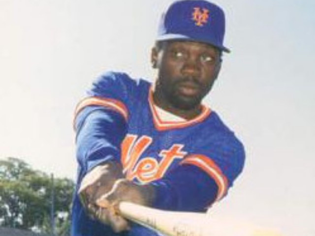 William Hayward Mookie Wilson is wearing a blue and orange baseball uniform and swinging a wooden bat