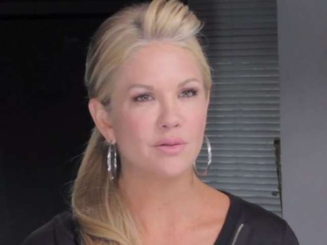 Nancy O'Dell with her hair in a ponytail, a black top, and silver hoop earrings. 