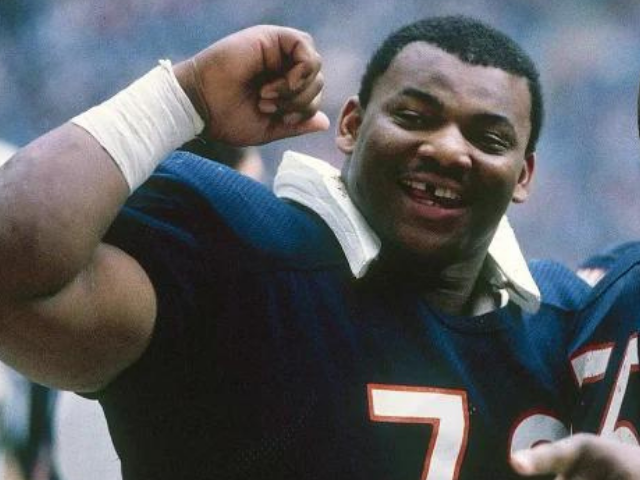 A smiling William "The Refrigerator" Perry flexing his arm while in his Chicago Bears uniform 