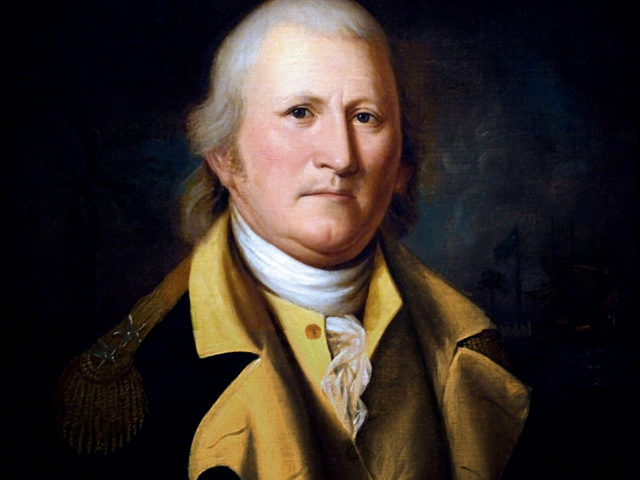 William Moultrie wearing a dark coat with a mustard yellow colored waistcoat and collar. 