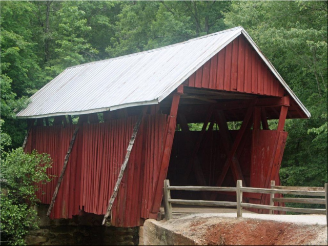 A red covered bridge with a white metal roof. 