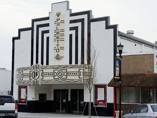 A black, white and cream movie theater with red accents on the two windows. 