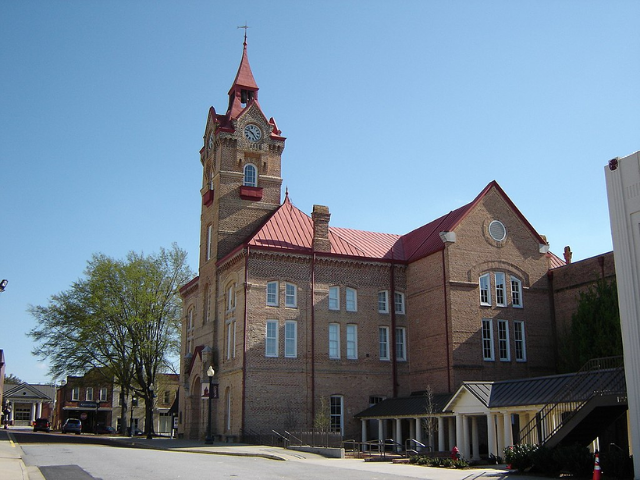 A large brown bricked building with rusted red roof tops. 