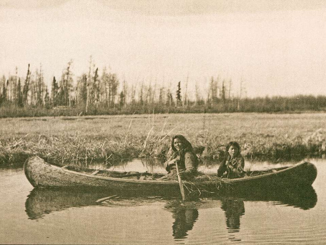 Two people on a canoe in the water. 