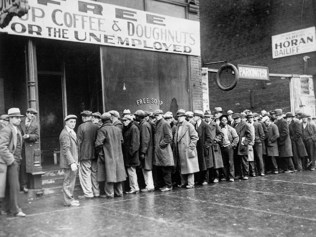 Men stand in a crowded line outside a building. 