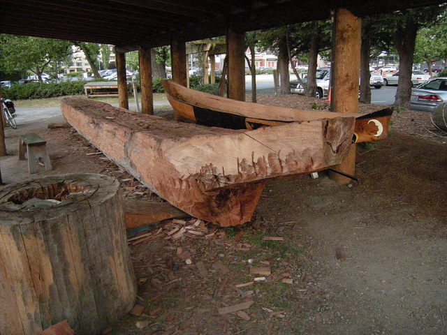 A large piece of wood being shaped into a canoe. 