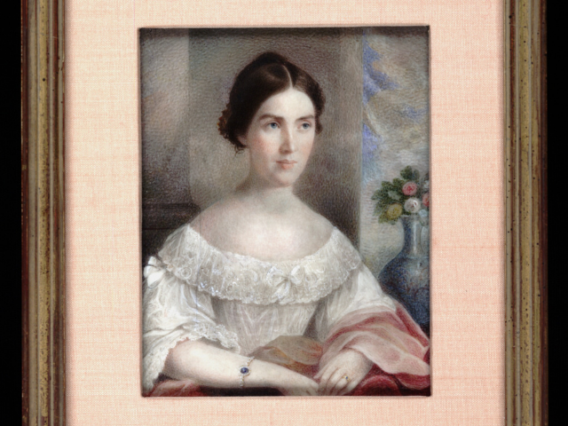 A young woman with dark hair wearing a white dress with a rose pink shawl