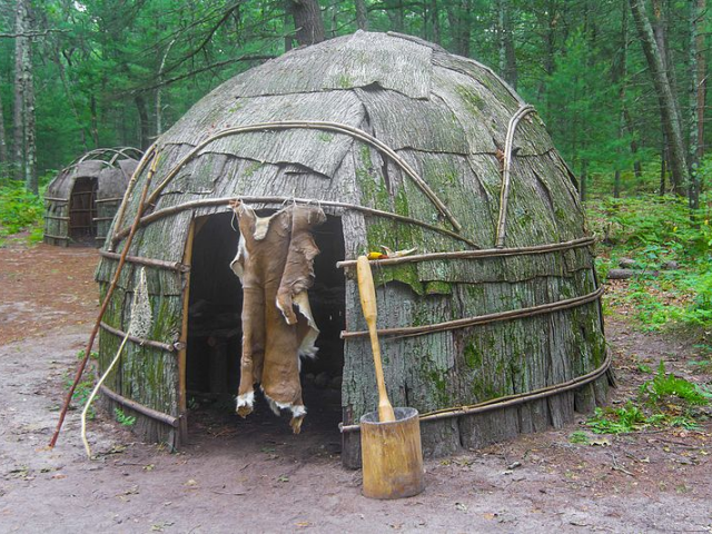 A circular hut covered with bark and curved tree sticks