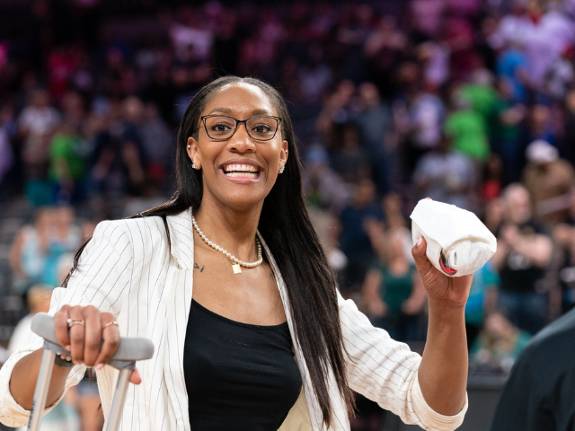 A'ja Wilson smiling and preparing to throw a wrapped up t-shirt to a crowd 