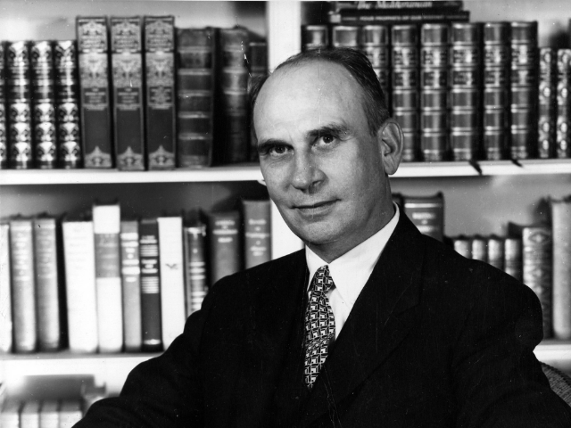 Black and white photo of Donald Russell smiling and posing in front of law books