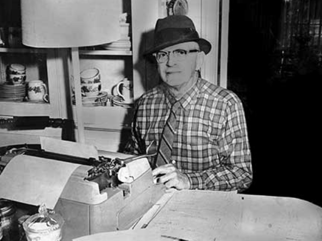 Black and white photograph of Babcock sitting in front of a typewriter