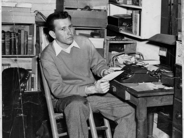 Black and white photograph of Max Steel sitting at a desk